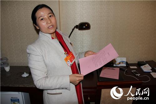 全国人大代表,湖北省五峰土家族自治县副县长张琼拿著会务方提供的